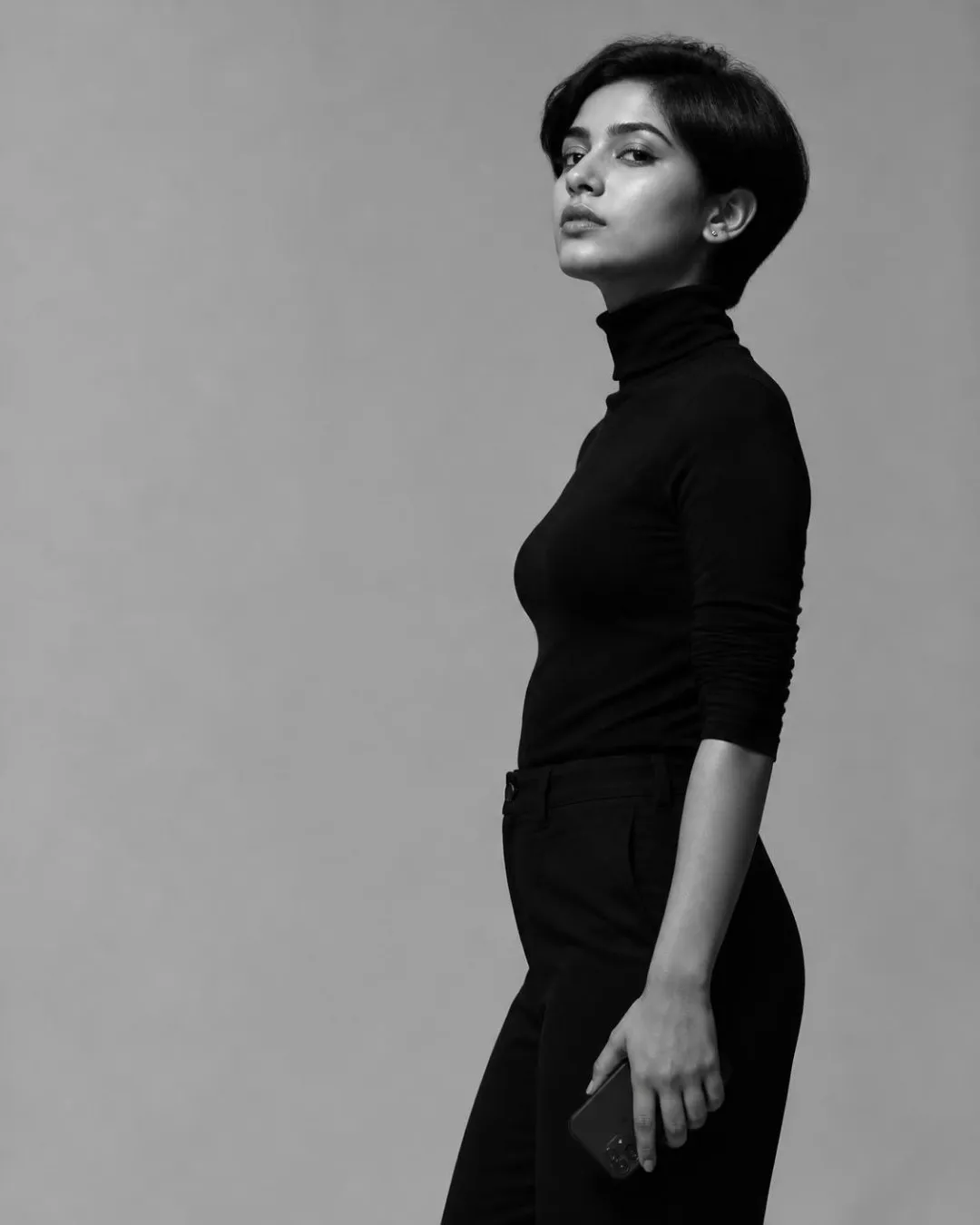 Creator in a black turtleneck holding her phone