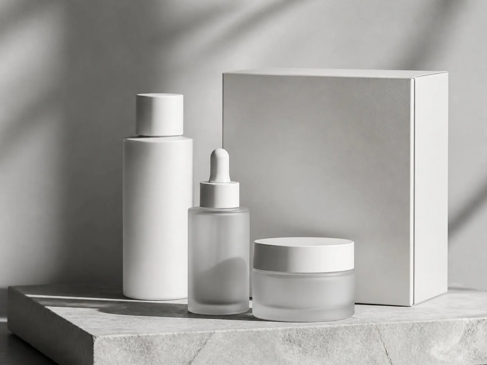 Minimal skincare bottles and packaging on a stone plinth